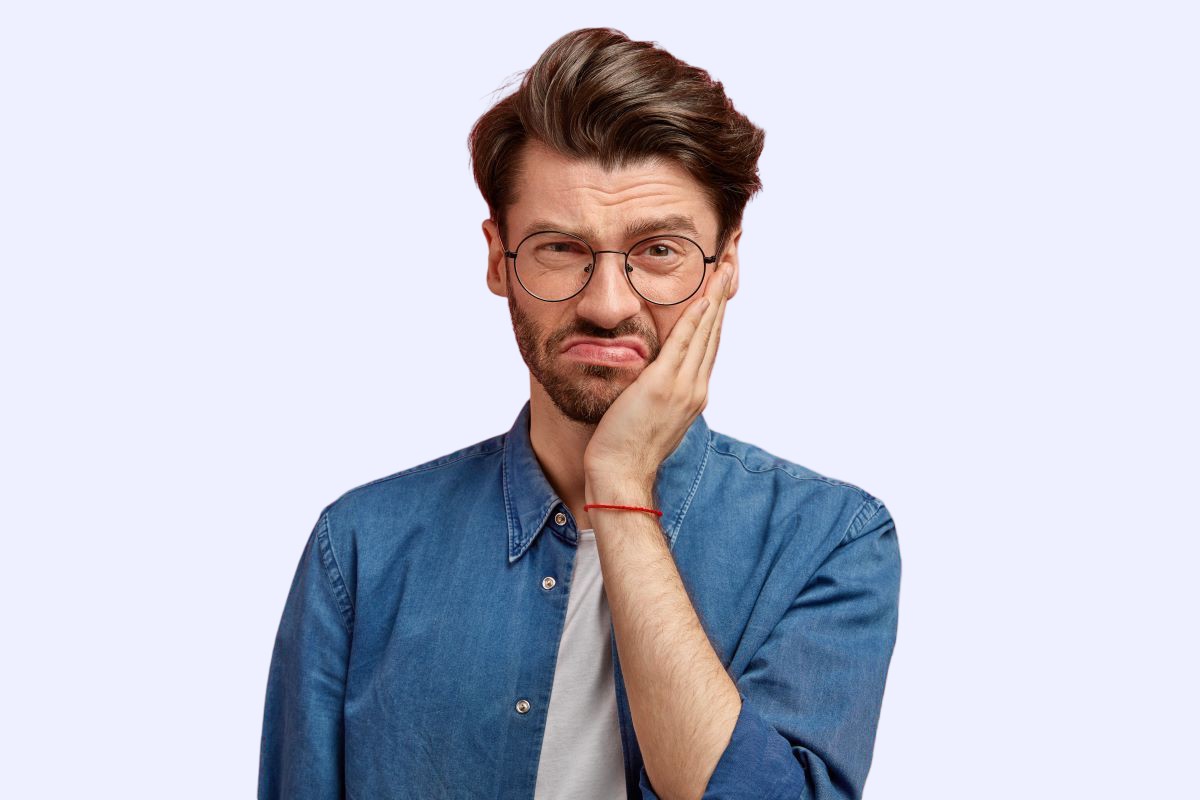 Tooth Extraction in Milton, Ontario | White Dove Dental Tooth extraction in Milton, man holding his cheek due to tooth pain before a gentle tooth removal at White Dove Dental
